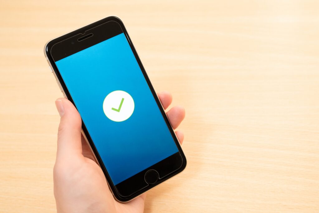 スマートフォンの画面に表示されたチェックマークを持つ手