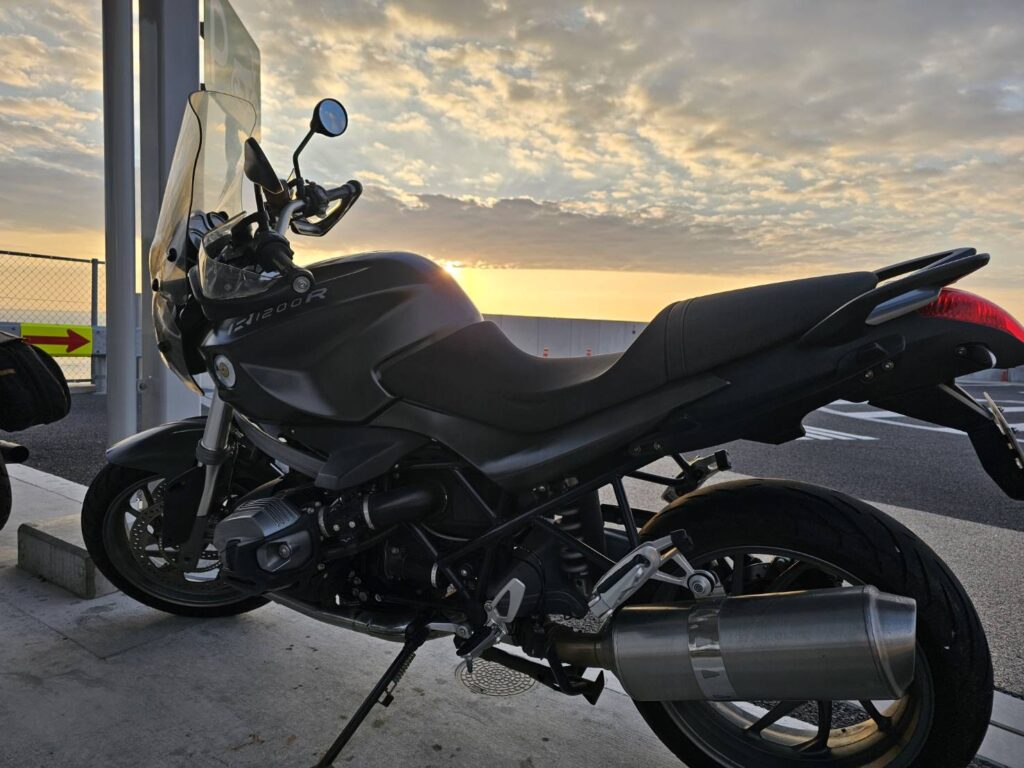 夕日と黒いバイクが映えるツーリング風景 - 美しい夕焼けとライダーの旅の象徴