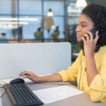 オフィスで電話対応をしながらパソコンを操作する女性スタッフ