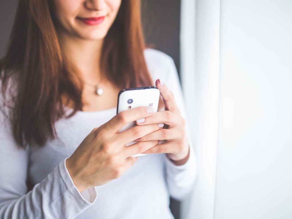 スマートフォンを操作する白い服の女性の手元
