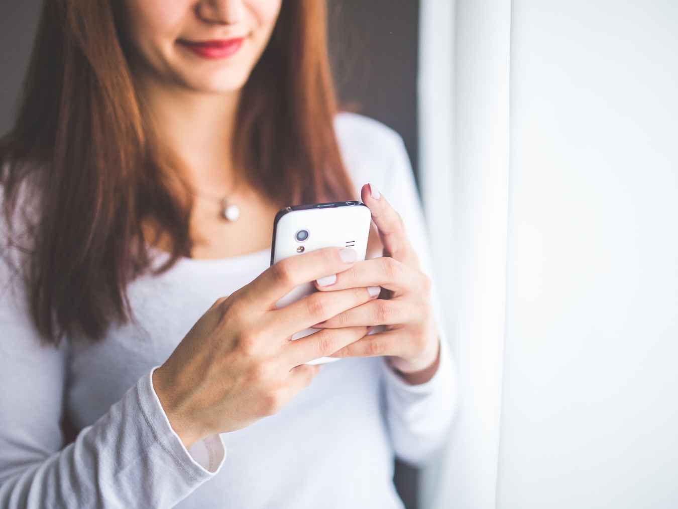 スマートフォンを操作する白い服の女性の手元