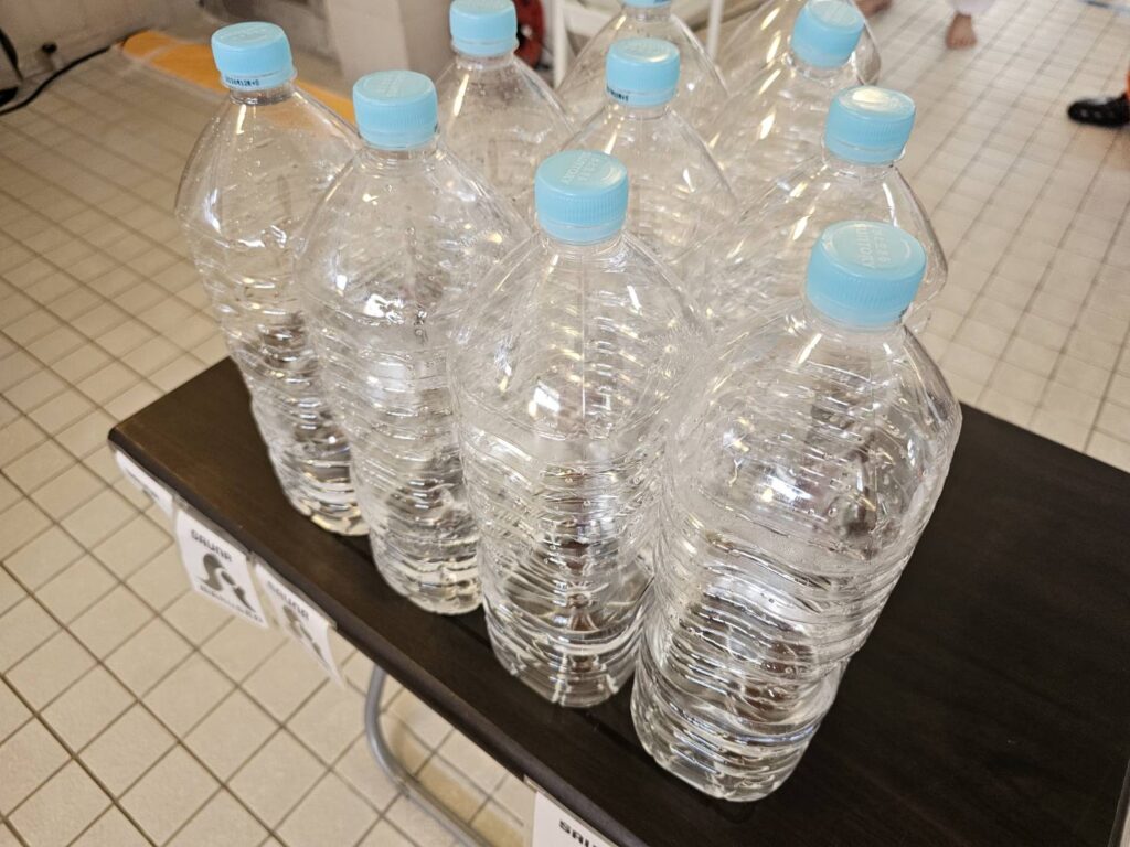 テーブルに整然と並べられた多数の空のペットボトル