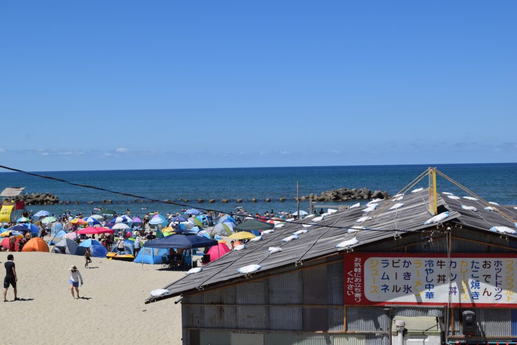 夏の海水浴場で多数のカラフルなテントやパラソルが並ぶにぎわう浜辺の風景