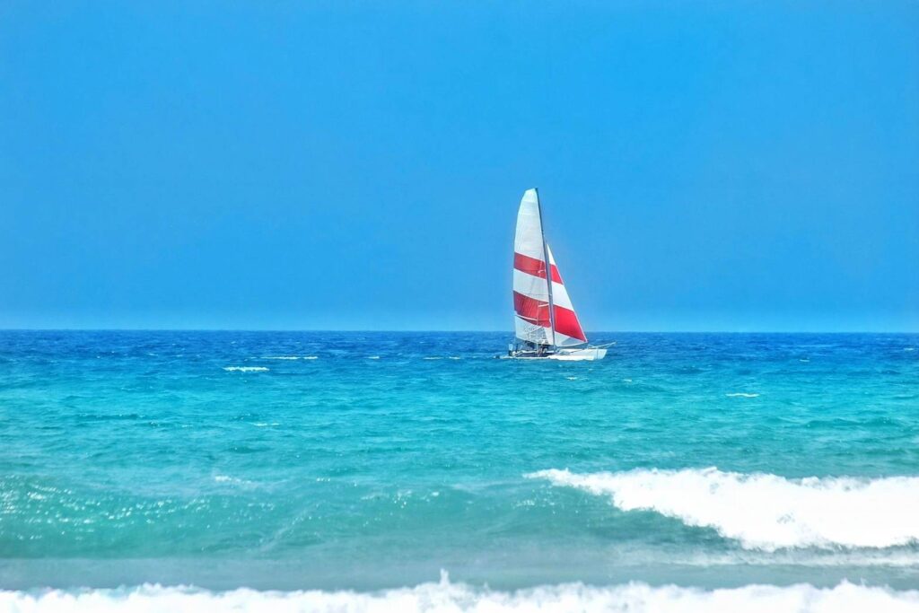 青い海を進む赤白の帆を張ったヨット