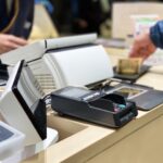 レジカウンターで現金支払いを行う様子と電子決済端末