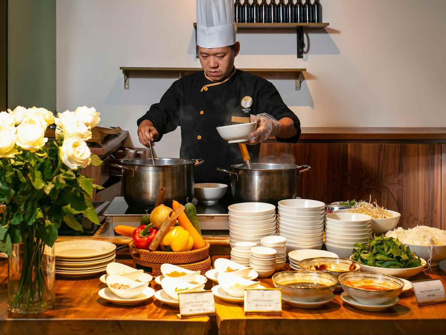 ホテルレストランでビュッフェ料理を提供するシェフと並べられた新鮮な食材と料理