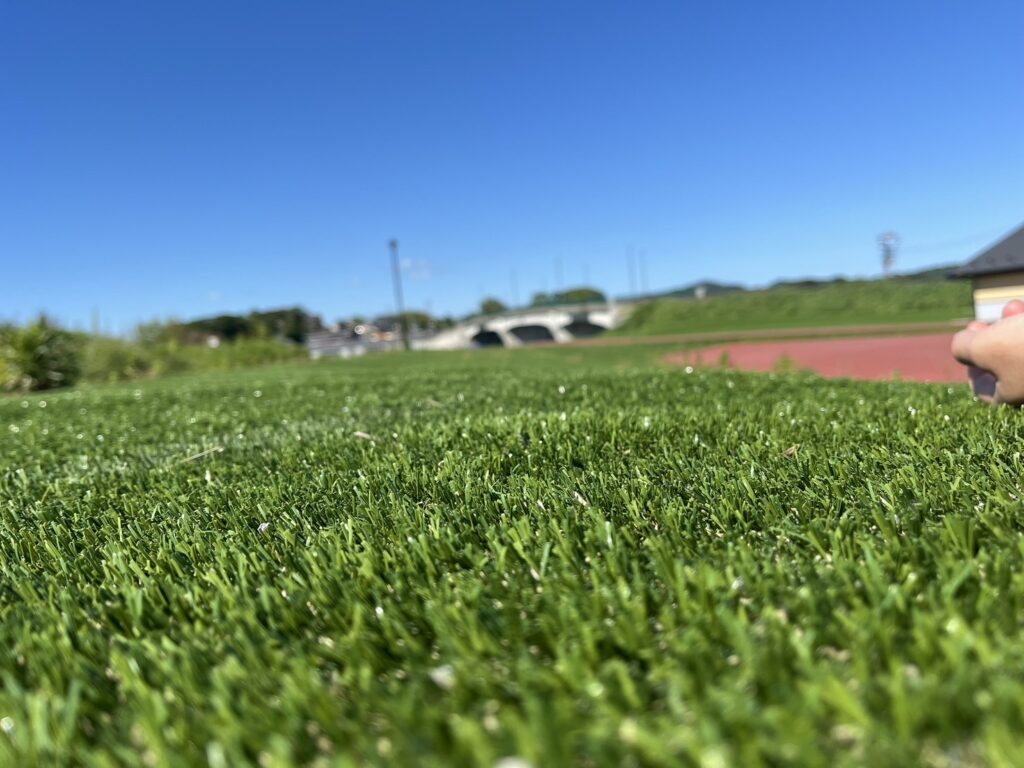 芝生の上から見上げた青空と遠景の橋が広がる風景