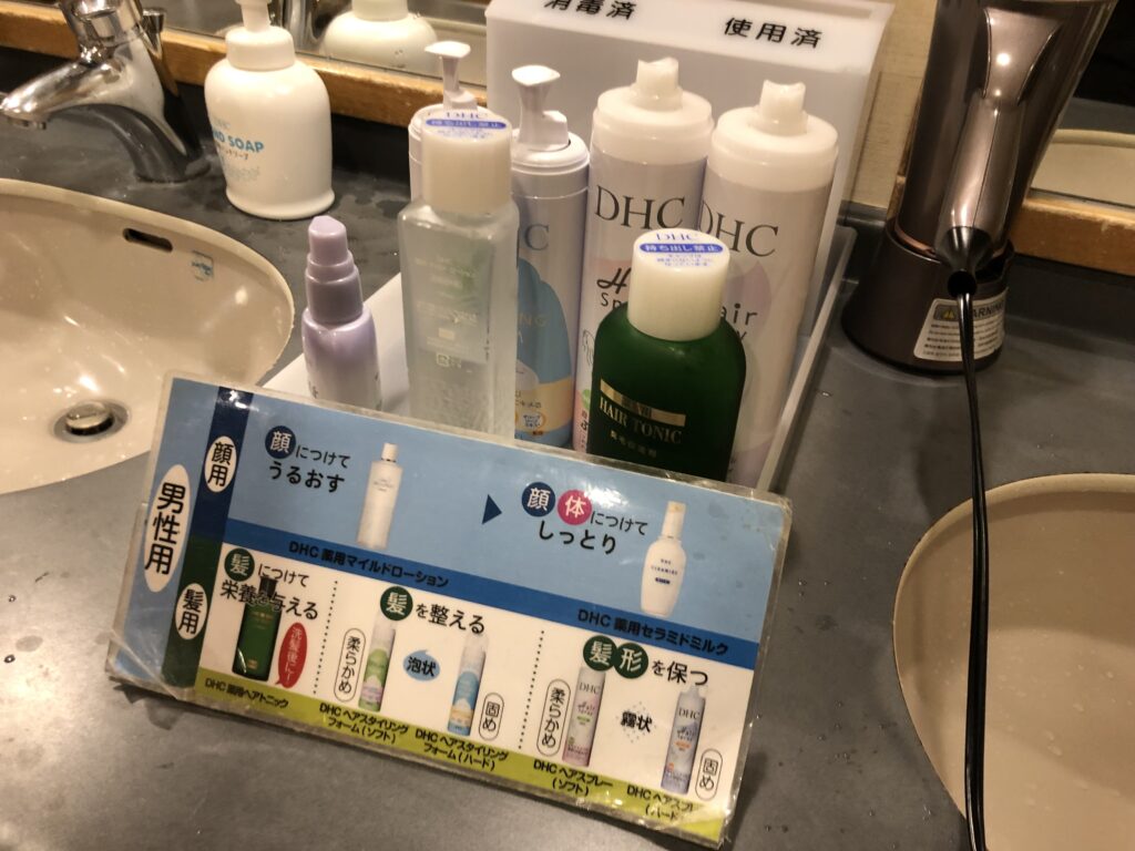 脱衣所の洗面台に並ぶDHC製の男性用スキンケアとヘアケアアメニティ