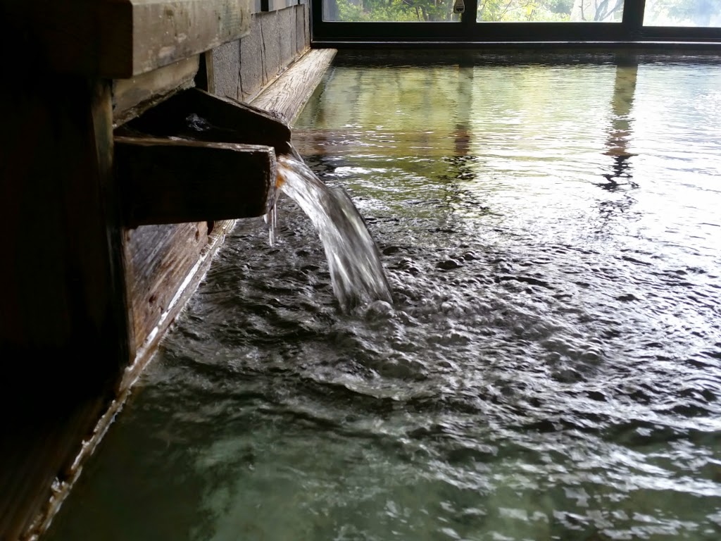 木製の湯口から源泉が流れ込む温泉浴槽
