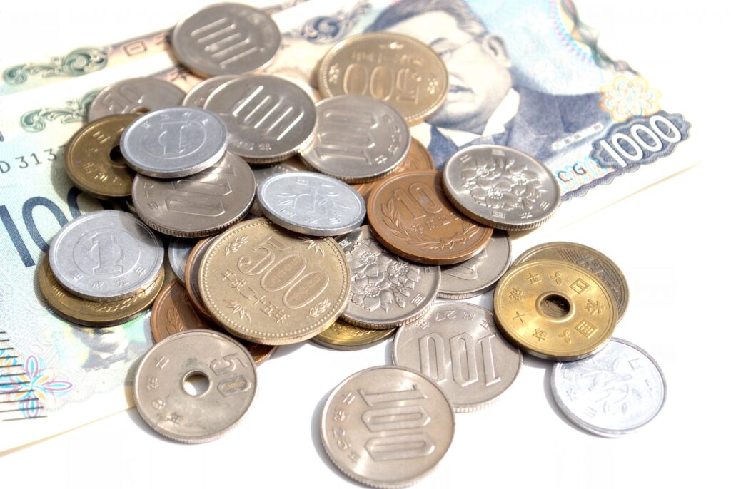 日本円の硬貨と千円札が並ぶ現金のイメージ