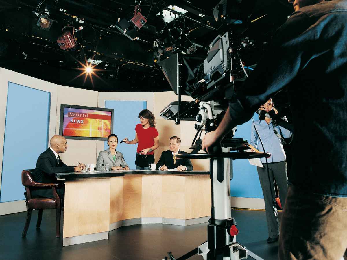 ニュース番組の撮影現場で打ち合わせを行うテレビスタッフとキャスターたち