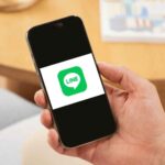 LINEアプリのロゴが表示されたスマートフォンを手に持つ様子