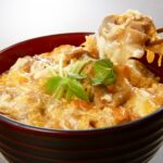 温かい親子丼を箸で持ち上げた瞬間の料理写真