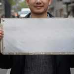 通りで白いボードを手に持つ男性