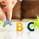 手がアルファベットのAをつまんで並べている様子、ABC分析のイメージ