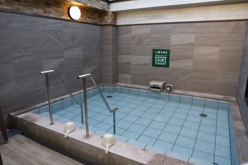 室内浴場の四角い湯船と手すりが設置された清潔な温浴設備