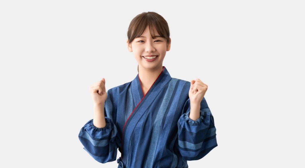 青い作務衣を着たスタッフが笑顔でガッツポーズをしている様子