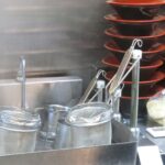 ラーメン店の厨房で麺を茹でるための湯切りざると器が並ぶ様子