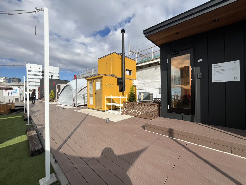 屋外展示場に並ぶサウナ小屋とテント型サウナを撮影した様子