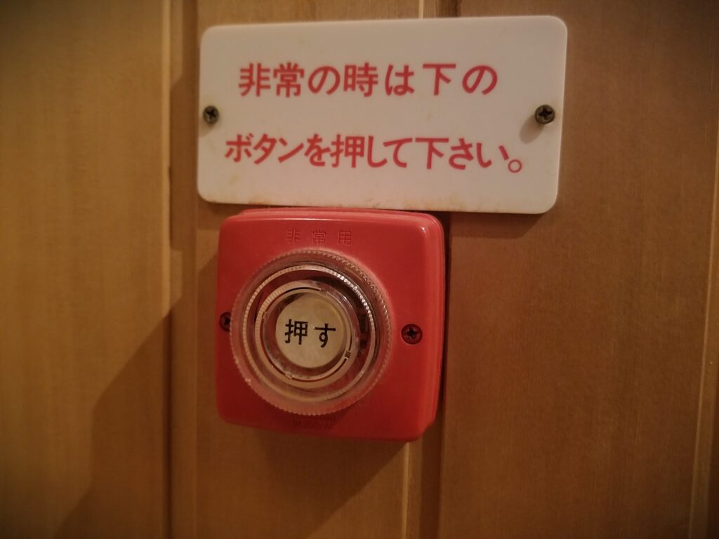 サウナ室内に設置された非常呼び出しボタンと非常時操作案内プレート
