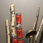 白樺の枝と赤いビール缶が室内の壁際に立てかけて配置されているサウナ装飾の様子。