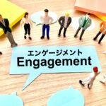机の上に並んだ人物フィギュアとEngagementと書かれた吹き出し型の紙が配置されている様子。