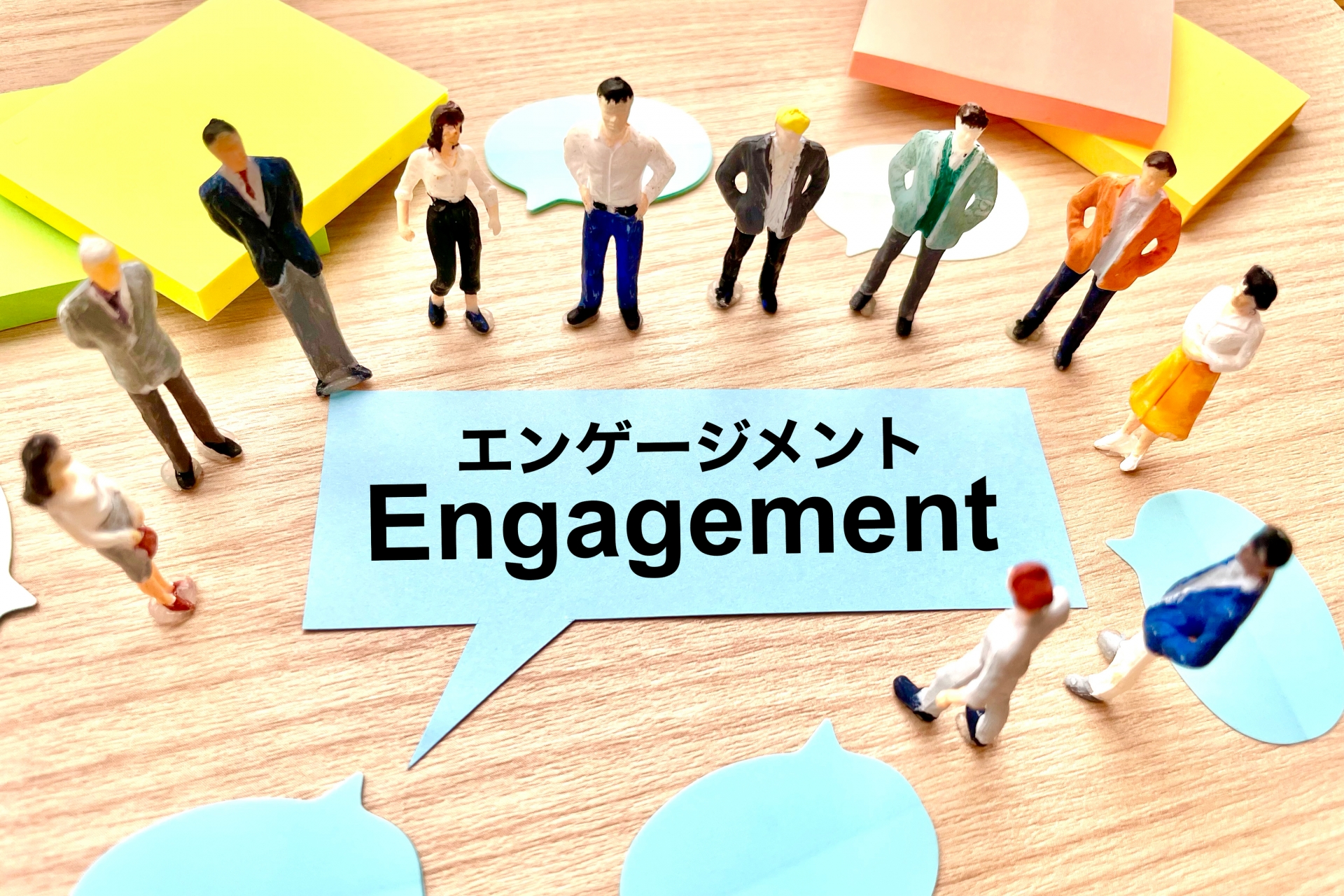机の上に並んだ人物フィギュアとEngagementと書かれた吹き出し型の紙が配置されている様子。