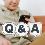 スマートフォンを操作する人物の前にQ&Aと書かれた吹き出しアイコンが配置されたSEOイメージ写真。