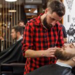理容室で男性スタッフが男性客の髭を整えている施術風景。