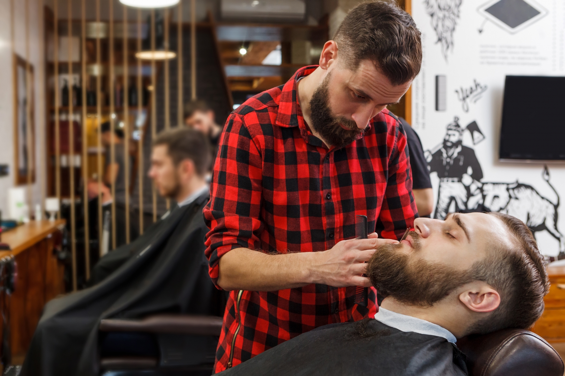 理容室で男性スタッフが男性客の髭を整えている施術風景。