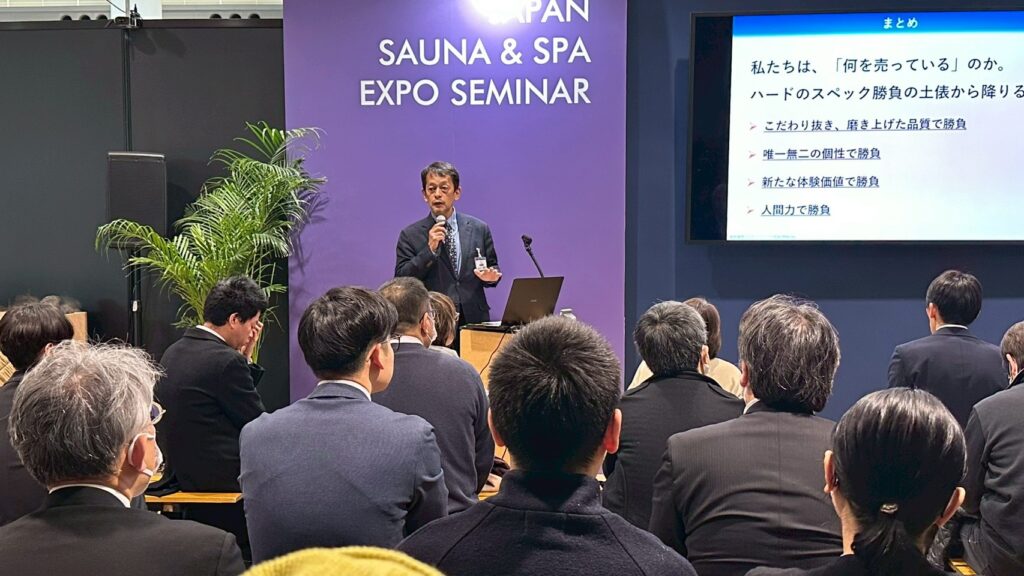 JAPAN SAUNA & SPA EXPO会場で温浴マーケット講演を行う登壇者と聴講者の様子。