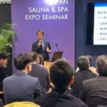 JAPAN SAUNA & SPA EXPO会場で温浴マーケット講演を行う登壇者と聴講者の様子。