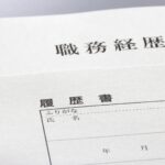 白い背景の上に温浴施設の求人応募などで使用される職務経歴書と履歴書の用紙が重ねて置かれています。