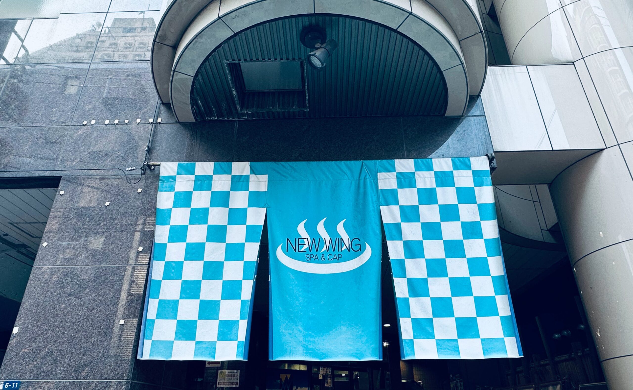 墨田区にあるサウナ施設ニューウイングの入り口に掲げられた水色と白の市松模様の暖簾