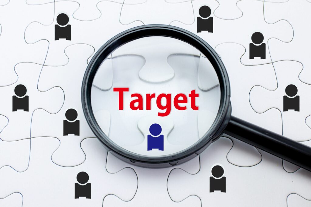 白いジグソーパズルの上で、虫眼鏡が「Target」という赤い文字と青い人物アイコンを拡大している様子