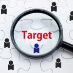 白いジグソーパズルの上で、虫眼鏡が「Target」という赤い文字と青い人物アイコンを拡大している様子