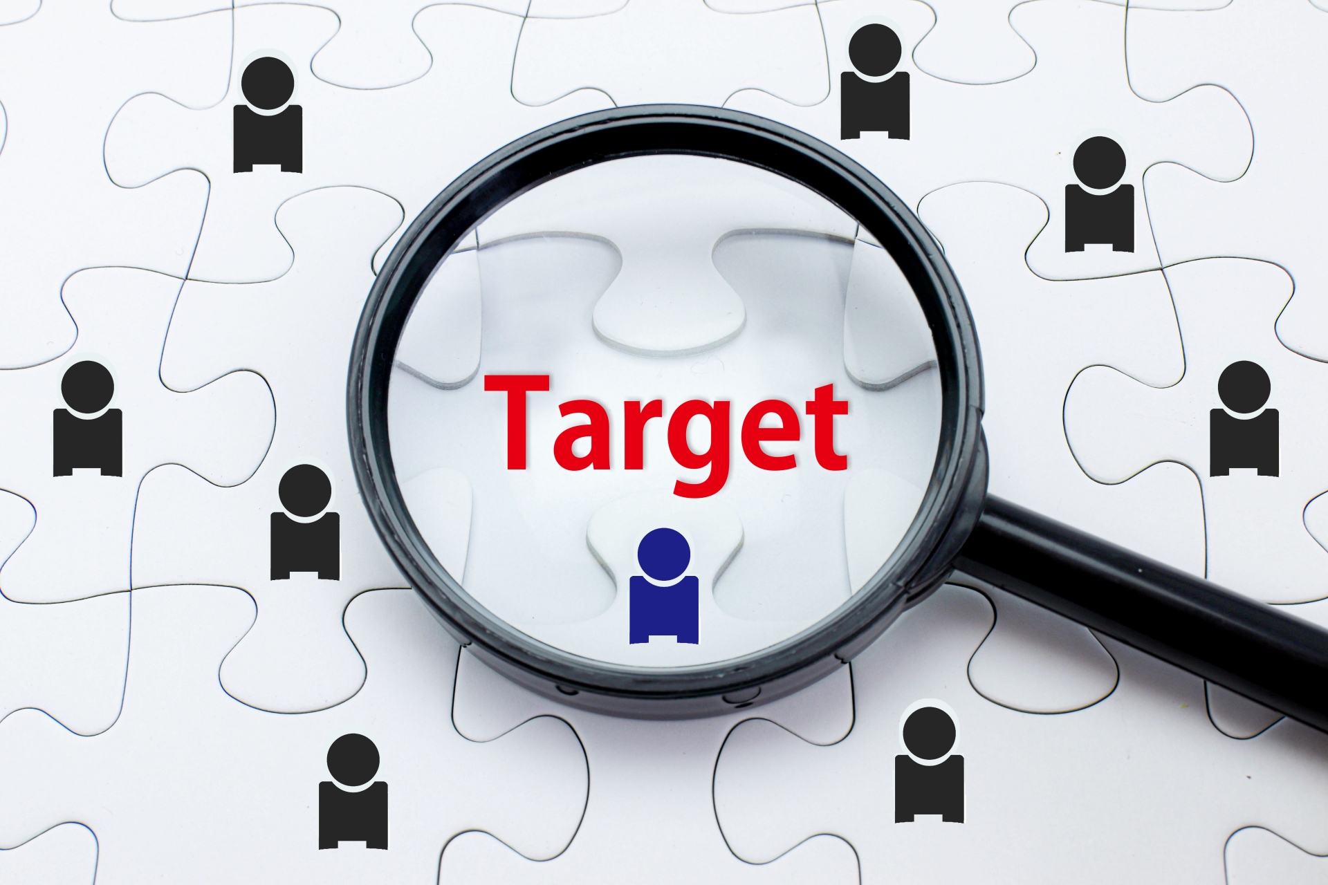 白いジグソーパズルの上で、虫眼鏡が「Target」という赤い文字と青い人物アイコンを拡大している様子