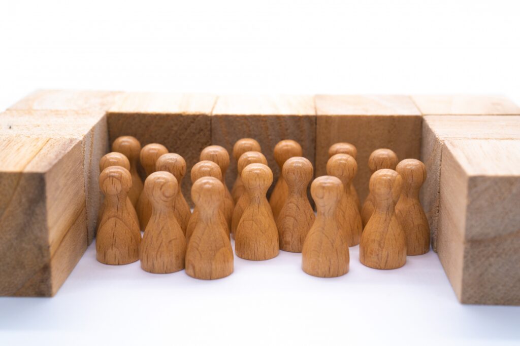木のブロックの枠内に密集する複数の人型の木製コマ