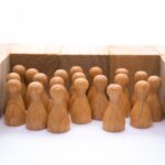 木のブロックの枠内に密集する複数の人型の木製コマ