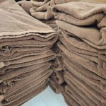 温浴施設の備品棚に、茶色のフェイスタオルが整然と高く積み上げられています
