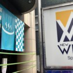 サウナ施設ニューウイングの入り口にある青と白の市松模様ののぼりとロゴ看板。