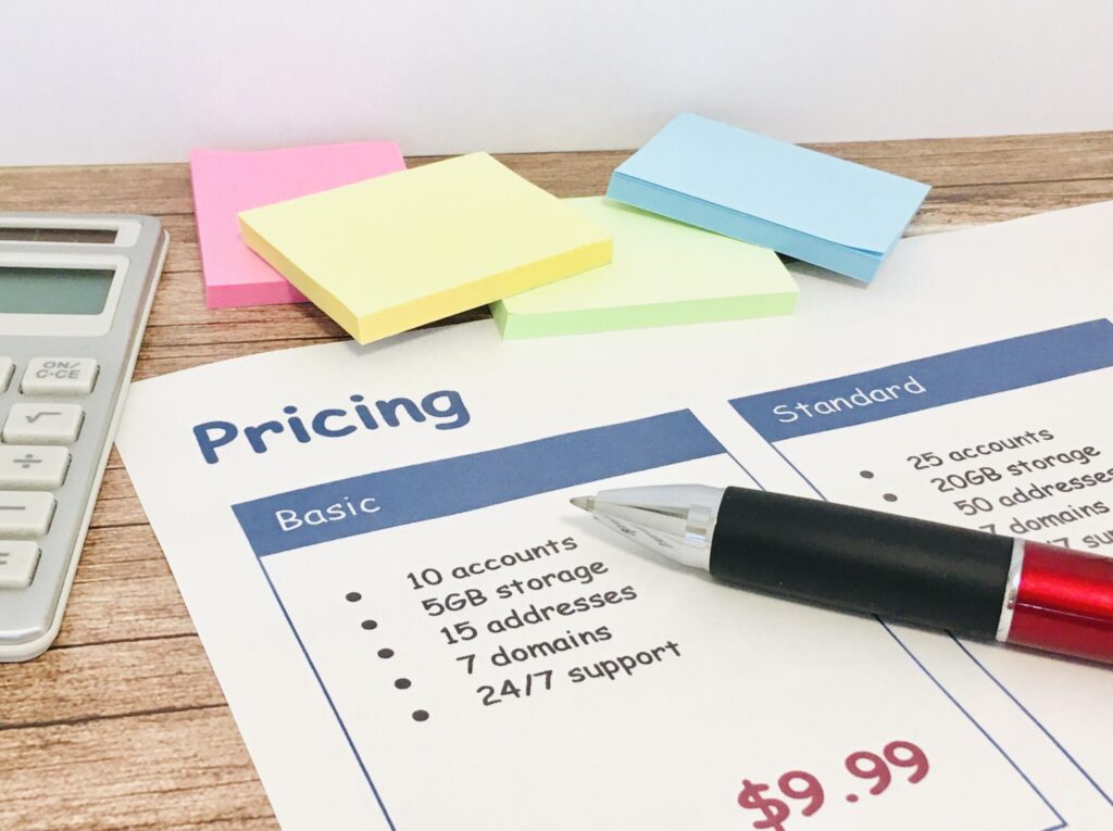 電卓と付箋の横に置かれた料金表にボールペンが添えられています。