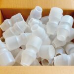 段ボール箱の中に温浴施設の集客事例に関わる大量の半透明の飲料向け空き容器が収められています。