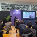 JAPAN SAUNA & SPA EXPOのセミナー会場で、スクリーンを使いながら講演を行う二人の登壇者とそれを見守る聴衆