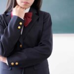 腕を組んで考え事をしている制服姿の女子高生を通して組織運営の課題を表現しています。