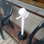 外気浴スペースのデッキチェアの間に設置された、白い手桶と専用のスタンド。