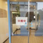 温浴施設のガラス張りの自動ドアに休館中と書かれた白い紙が貼り出されている様子