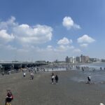 温浴施設の体験型集客の参考となる、干潮時に出現した江の島の砂州を歩いて渡る人々の風景です。