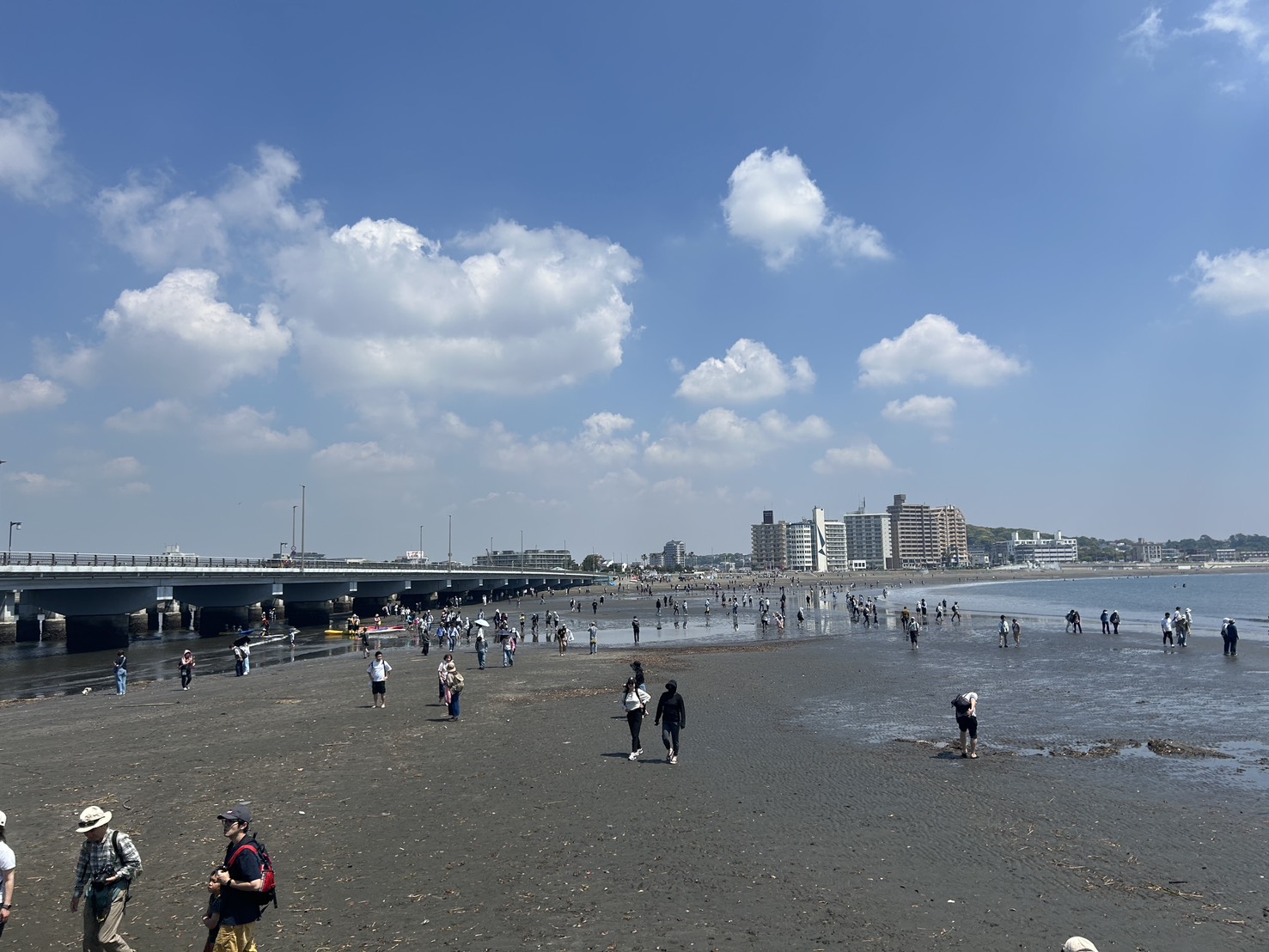 温浴施設の体験型集客の参考となる、干潮時に出現した江の島の砂州を歩いて渡る人々の風景です。