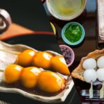 和風カフェで提供される、串に刺さったみたらし団子と自分で焼くための白い団子、餡や抹茶のソース、小さな七輪が並ぶ様子